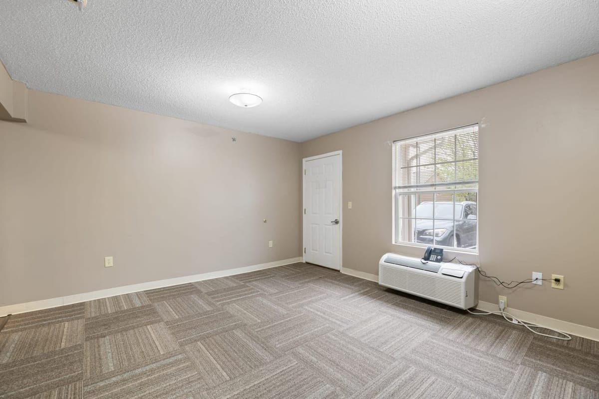 A bright, private resident apartment at BelVilla with a large window.