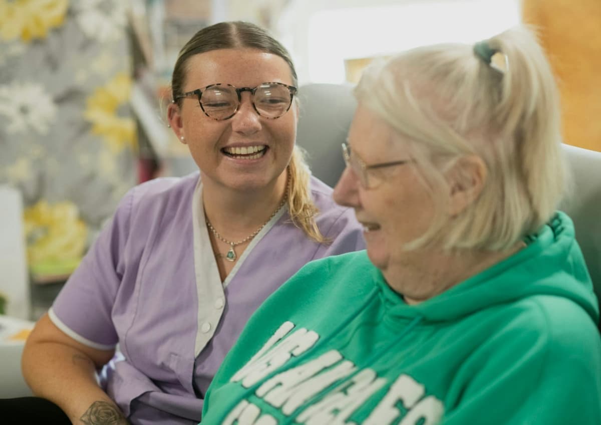 A caregiver and a resident laughing together.